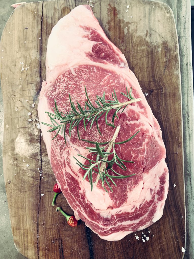 Raw steak with rosemary twigs